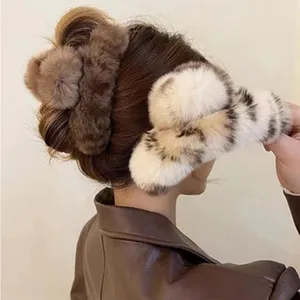 Detail view of two fluffy faux fur hair claws in brown and white on messy hair bun