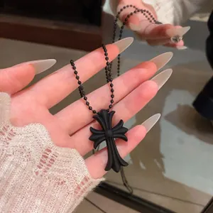 Detailed close-up showing a matte black gothic cross necklace with a beaded chain design.
