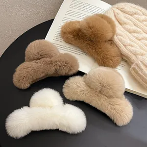 Close-up of four large plush hair claw clips in warm autumn and winter neutral colors.