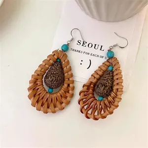 Close-up of bohemian rattan woven teardrop earrings with turquoise and wood beads.