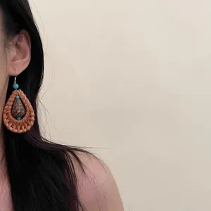 Bohemian rattan woven teardrop earrings shown worn on model for a beach holiday style.