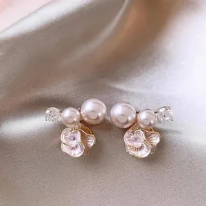 Close-up of elegant petal pearl earrings with sparkling crystals on silk background