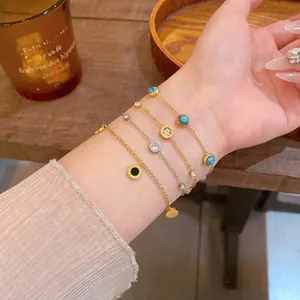 Close-up of elegant gold and silver bracelets with turquoise and zircon on wrist