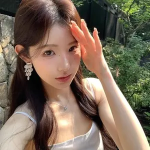 Modella asiatica indossa eleganti orecchini a petalo bianco con luce naturale