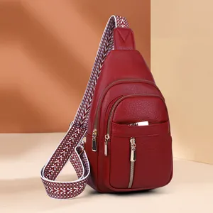 Close-up detail of the textured red leather sling bag with a bohemian wide strap.