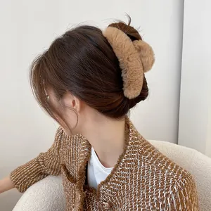 Detailed view of a plush faux fur hair claw clip in camel color styled on a woman's hair