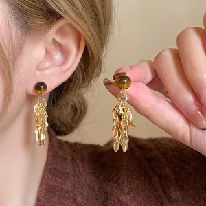 Close-up of Maillard style acrylic resin dangle earrings with gold leaf tassel details
