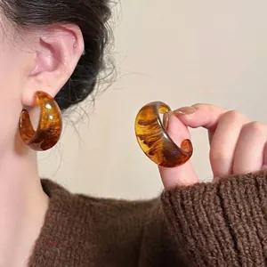 Detail view of amber resin hoop earrings with Maillard style brown texture