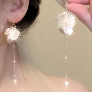 Close-up detail of elegant French style petal and pearl dangling earrings on a model