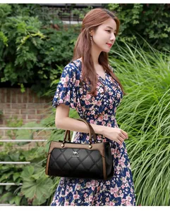 Elegant black quilted handbag with kangaroo logo carried by a woman in a floral dress