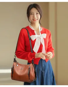 Modelo asiática con un elegante bolso bandolera de cuero marrón con varios compartimentos