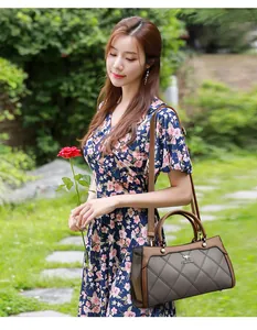 Elegant quilted handbag with brown and grey patchwork shown by an Asian model in garden