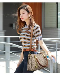 Side view of a stylish printed handbag with a kangaroo gold charm held by a model.