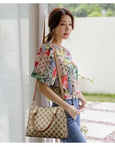 Detail view of a stylish checkered crossbody bag worn by an Asian model in natural light.