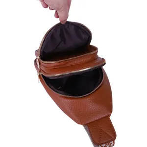 Detailed view of women's brown leather chest bag showing multiple open zipper compartments