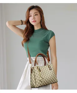 Close-up of a stylish printed crossbody handbag featuring brown handles and a gold charm