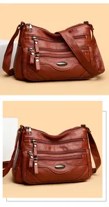 Detailed close-up view of brown leather crossbody bag featuring multiple functional zippers