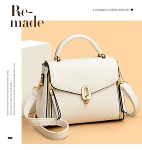 Close-up detail of stylish white leather handbag featuring gold clasp and handle