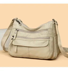 Vue détaillée d'un sac à bandoulière en cuir lavé beige avec plusieurs poches zippées.