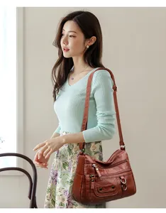 Elegant Asian model carrying a soft brown leather multi-pocket crossbody shoulder bag.