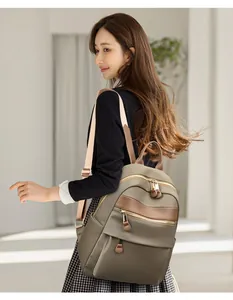 Elegante Asiatin mit khakifarbenem Nylonrucksack in einem minimalistischen Studio.