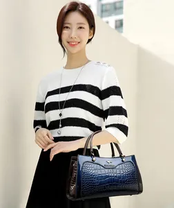 Close-up detail of retro blue crocodile embossed patent leather handbag with metal logo