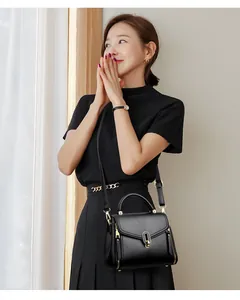 Detail of elegant black crossbody bag with gold hardware and top handle.