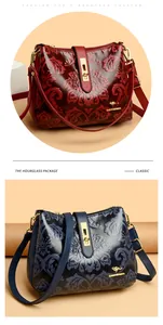 Detail of retro embossed floral pattern on leather crossbody bags in burgundy and navy blue.
