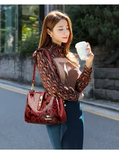 Elegant retro burgundy patterned shoulder bag carried by a model on a city street