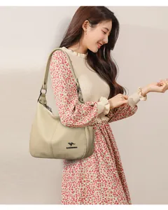 Detail view of beige pebbled leather shoulder bag with golden kangaroo logo