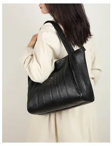 Elegante grote zwarte kunstlederen shopper met geplooid ontwerp gedragen door model