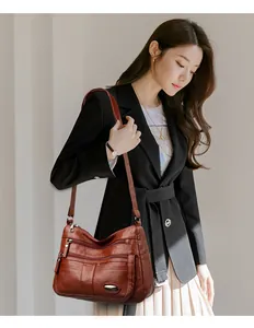 Stylish brown multi-pocket leather shoulder bag modeled by a woman in professional attire
