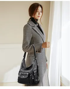 Stylish black leather convertible handbag held by an elegant woman in a houndstooth coat