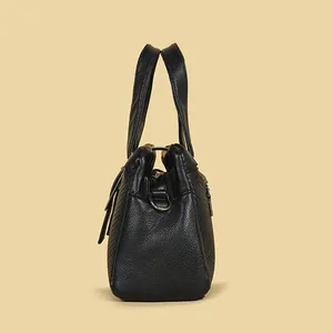 Seitenansicht der schwarzen Handtasche aus geprägtem Leder mit Textur und Metallteilen.