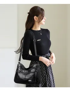 Elegant Asian model carrying a black multi-pocket leather crossbody bag in a studio setting