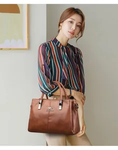 Primer plano de modelo asiática sosteniendo un bolso marrón elegante con asas tejidas y plata