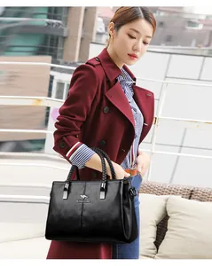 Elegante bolso de mano de cuero negro texturizado llevado por una modelo en abrigo rojo