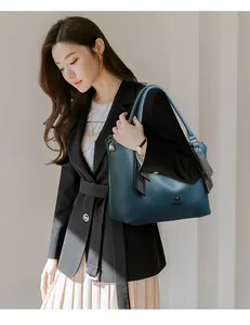 Elegante bolso de hombro de cuero azul con una chaqueta negra hoy en una modelo.