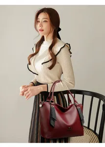 Detalle de un elegante bolso de cuero burdeos llevado por una modelo en un estudio pro