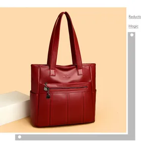 Detalle del bolso tote de piel roja suave con cremallera frontal y bolsillos laterales.