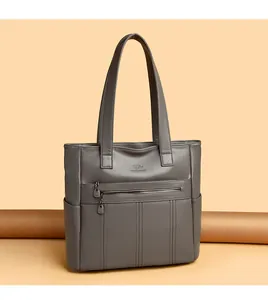 Vista detallada del bolso tote de piel suave gris con correas para el hombro.