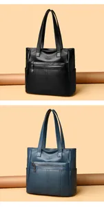 Exhibición vertical de bolsos tote de cuero suave negro y azul con detalle de cremallera.