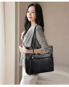 Mujer asiática que lleva un gran bolso tote de cuero suave negro con bolsillos laterales