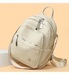 Detailed view of cream soft leather backpack featuring multiple zippers and pebble texture