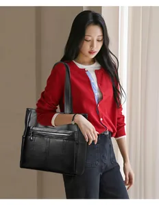 Elegante modelo asiática llevando un gran bolso tote de cuero suave negro con cremallera.