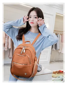 Stylish tan soft leather backpack with multiple zippers worn by a model in a boutique