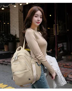 Model wearing a beige soft leather backpack with multi-pocket design for daily fashion