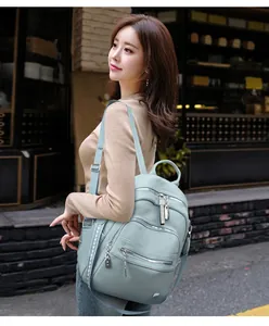 Stylish light blue soft leather backpack worn by model in outdoor street setting