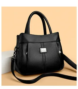 Close-up detail of black litchi pattern leather handbag with metal logo plaque