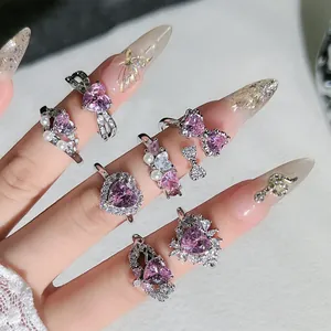 Primer plano de elegantes anillos de cristal rosa en forma de corazón y acabado plata.
